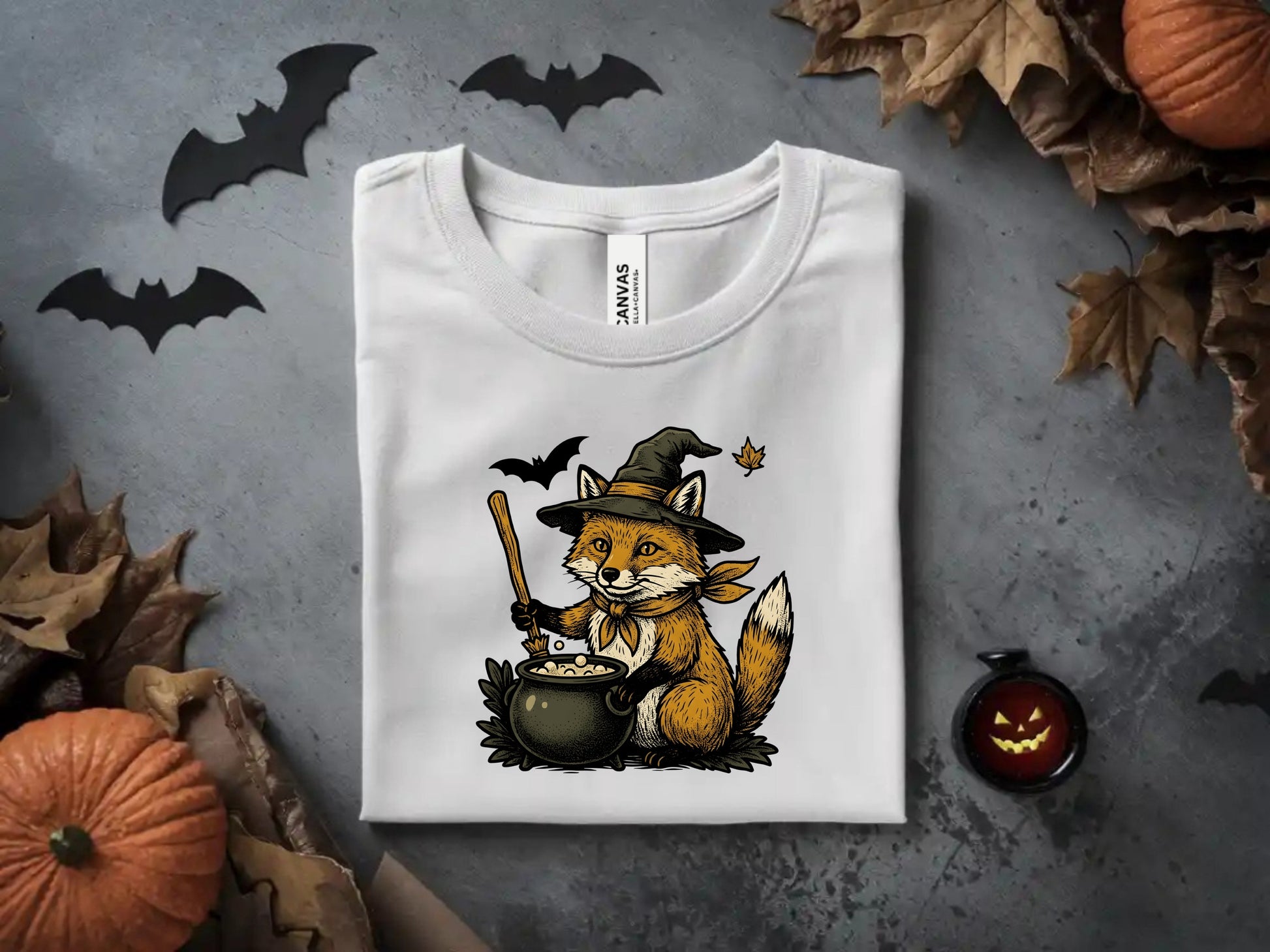 White t-shirt with a graphic of a fox in a witch hat stirring a cauldron.
