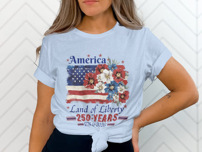 Light blue t-shirt with American flag, flowers, and text "America Land of Liberty 250 Years 1776 to 2026".