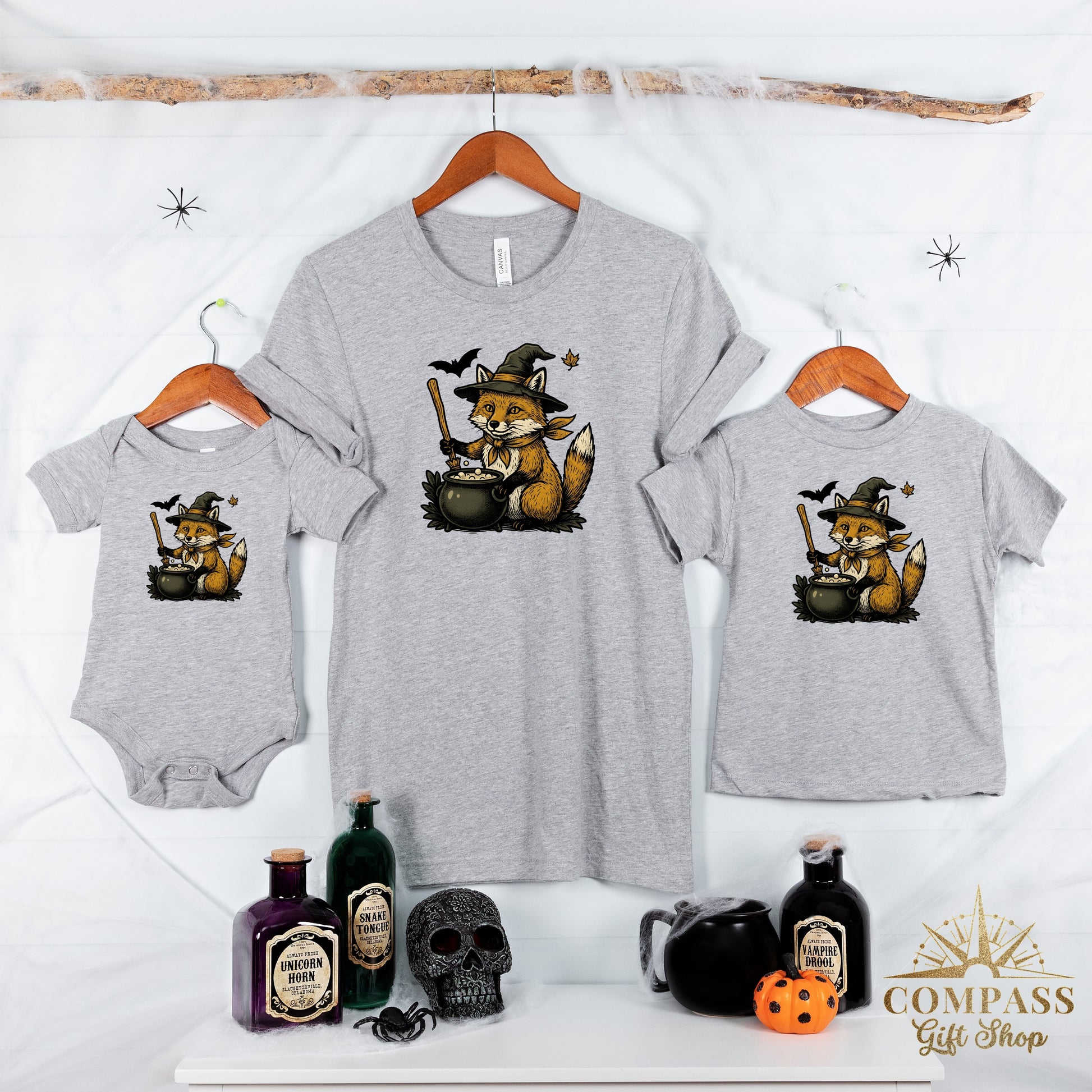 Grey t-shirts and onesie display a Halloween fox graphic with a witch hat and cauldron.