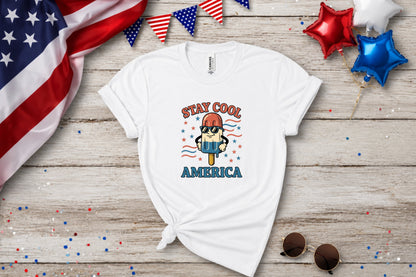 White t-shirt with "STAY COOL AMERICA" and popsicle graphic, with patriotic decorations.