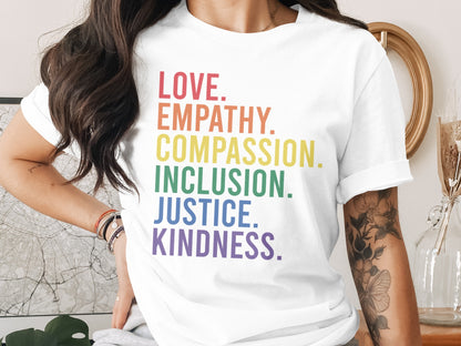 White t-shirt with "LOVE. EMPATHY. COMPASSION. INCLUSION. JUSTICE. KINDNESS." in rainbow colors.
