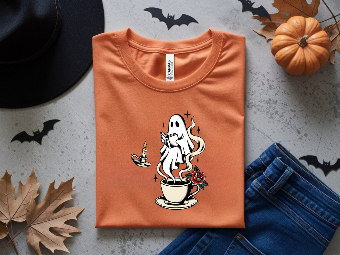 Orange t-shirt with ghost reading by candle and rose in coffee cup graphic.