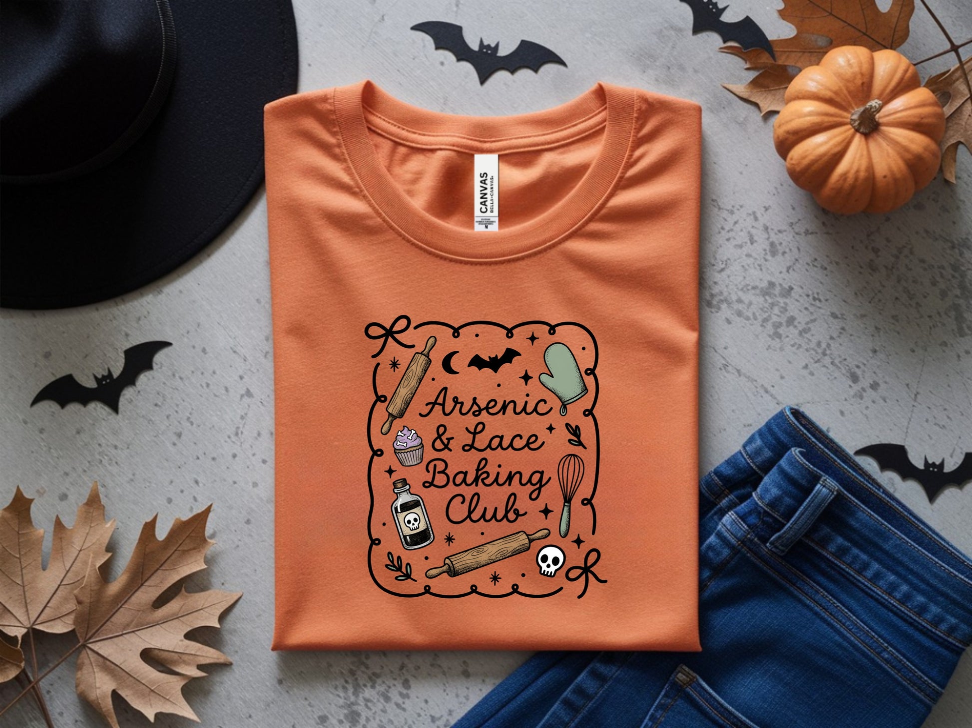 Orange t-shirt with "Arsenic & Lace Baking Club" text and Halloween-themed baking graphics.