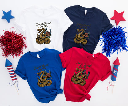 Four t-shirts in red, blue, white, and navy, each with "Don't Tread On Me" and a coiled snake graphic.