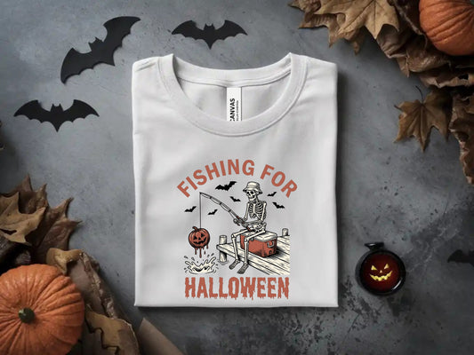 White t-shirt with skeleton fishing for Halloween on a pier with a pumpkin.