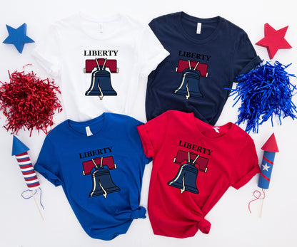 Four Liberty Bell t-shirts in white, navy, royal blue, and red.