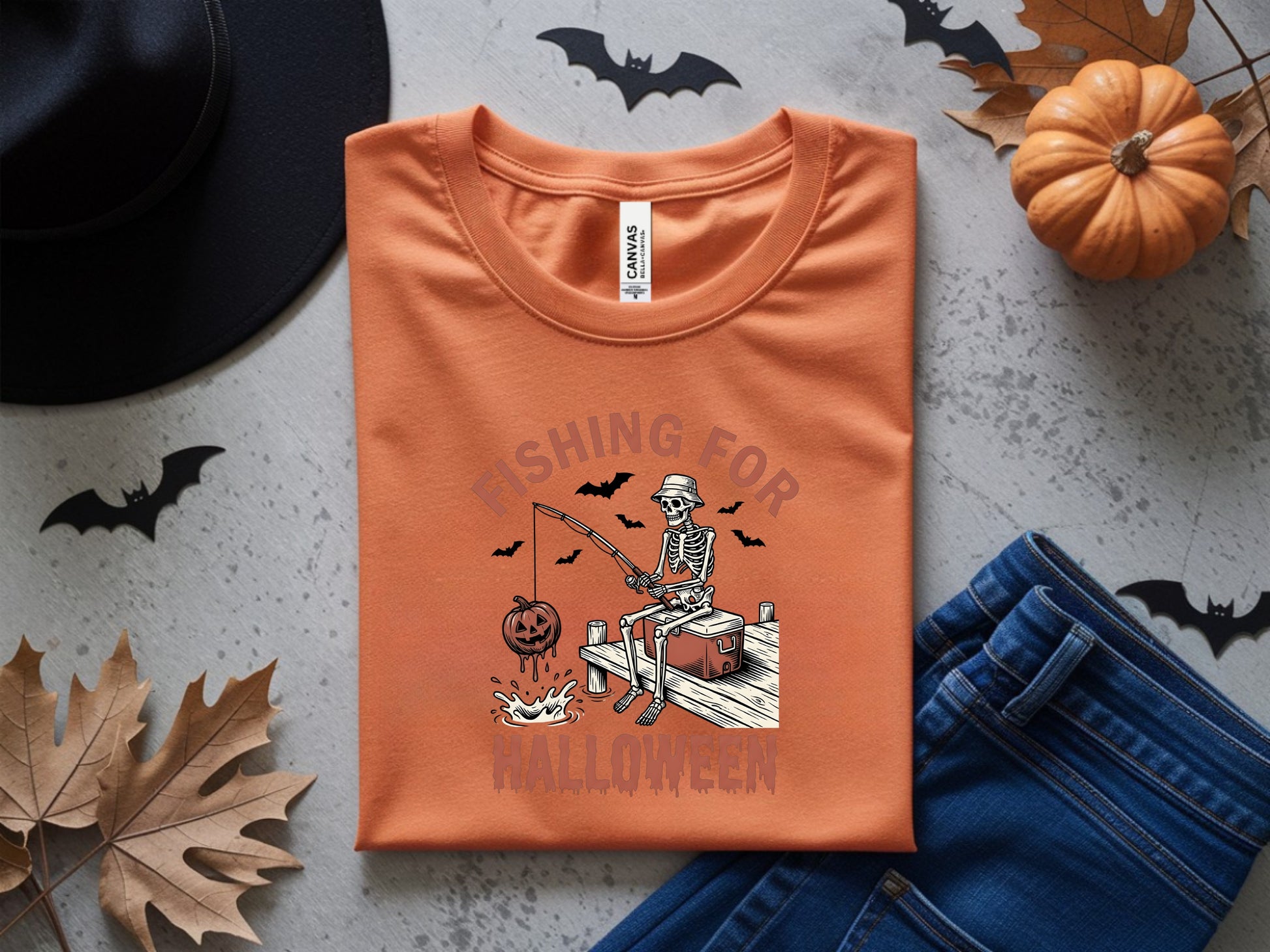 Orange t-shirt with skeleton fishing for Halloween graphic and pumpkins.