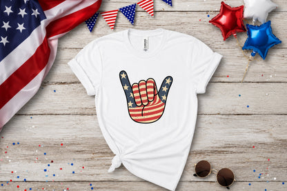 White t-shirt with American flag hand sign graphic and patriotic decorations.