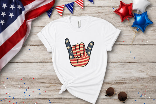 White t-shirt with American flag hand sign graphic and patriotic decorations.