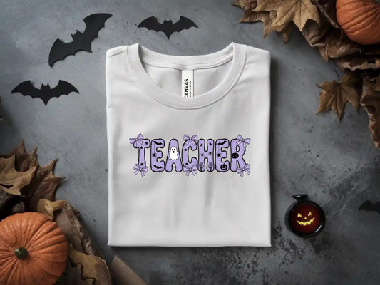 White t-shirt with "TEACHER" text featuring Halloween-themed graphic elements.