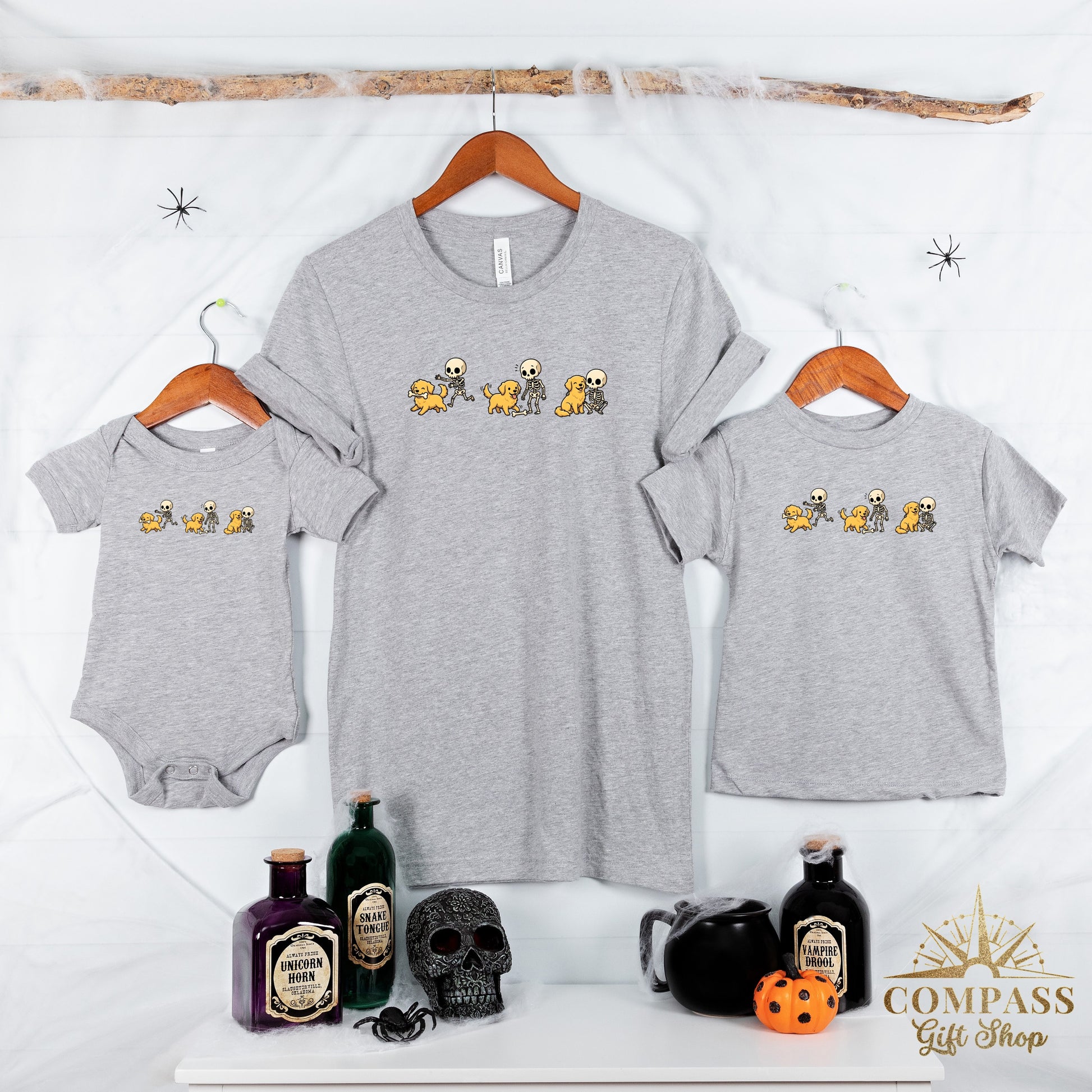 Grey shirts and a baby onesie feature a cartoon print of skeletons playing with dogs.