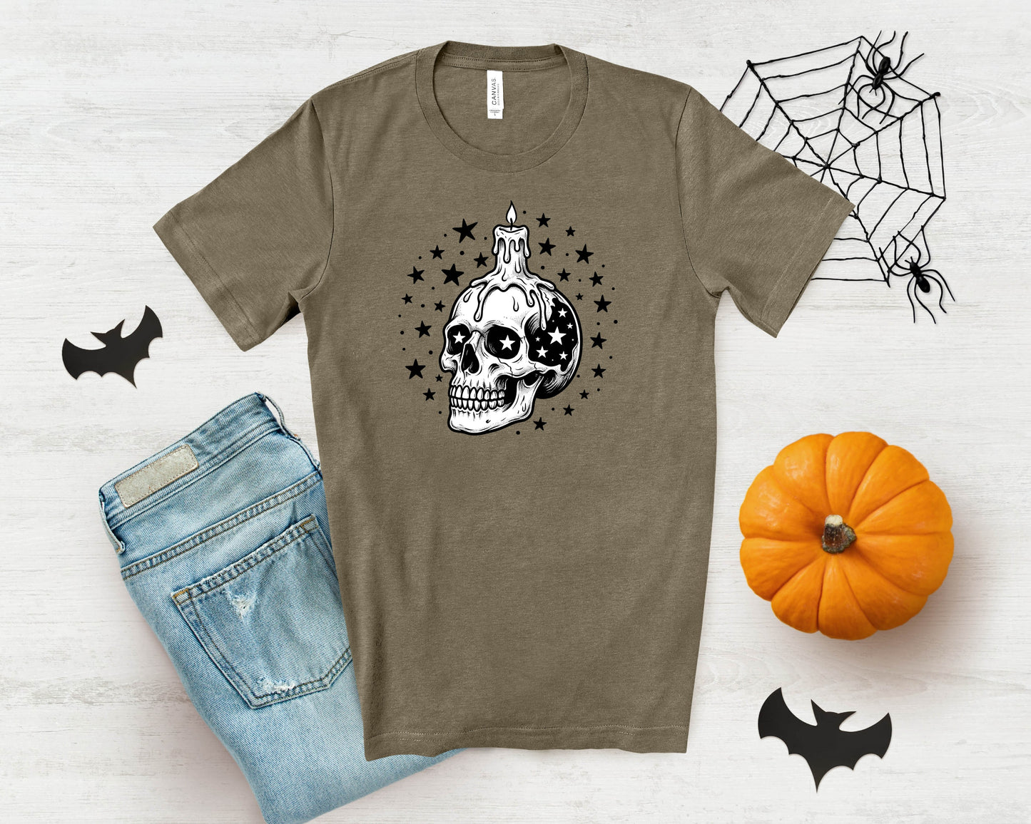 T-shirt with dripping candle skull graphic and stars, next to jeans and pumpkin.