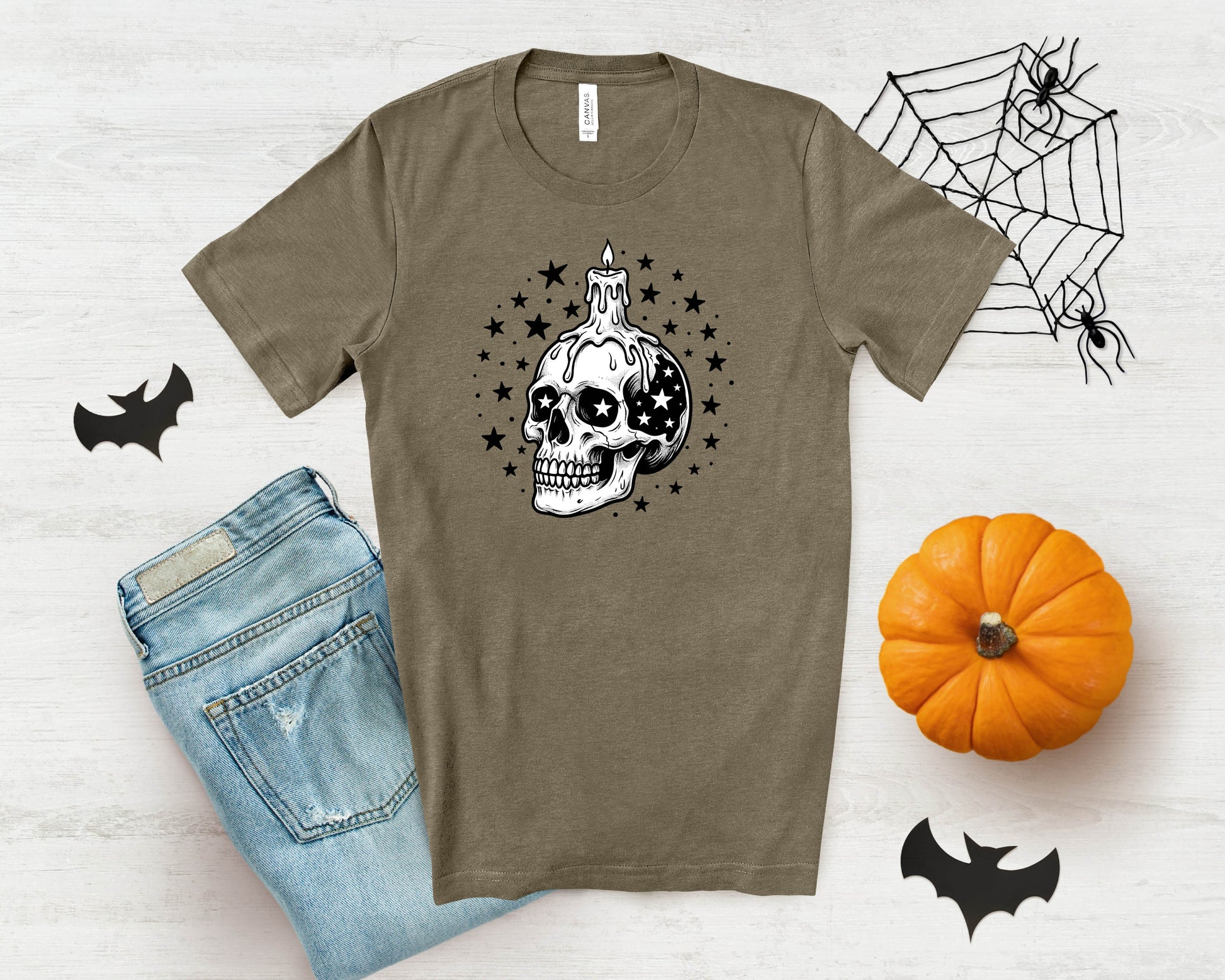 T-shirt with dripping candle skull graphic and stars, next to jeans and pumpkin.