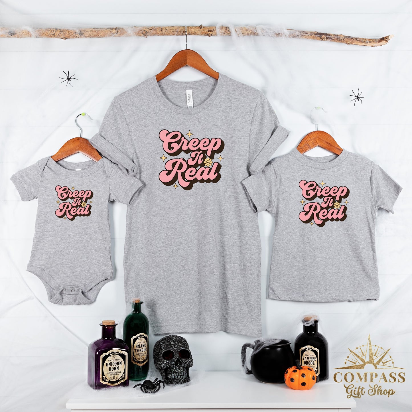 Three grey t-shirts, baby onesie displaying "Creep It Real" text and Halloween props.