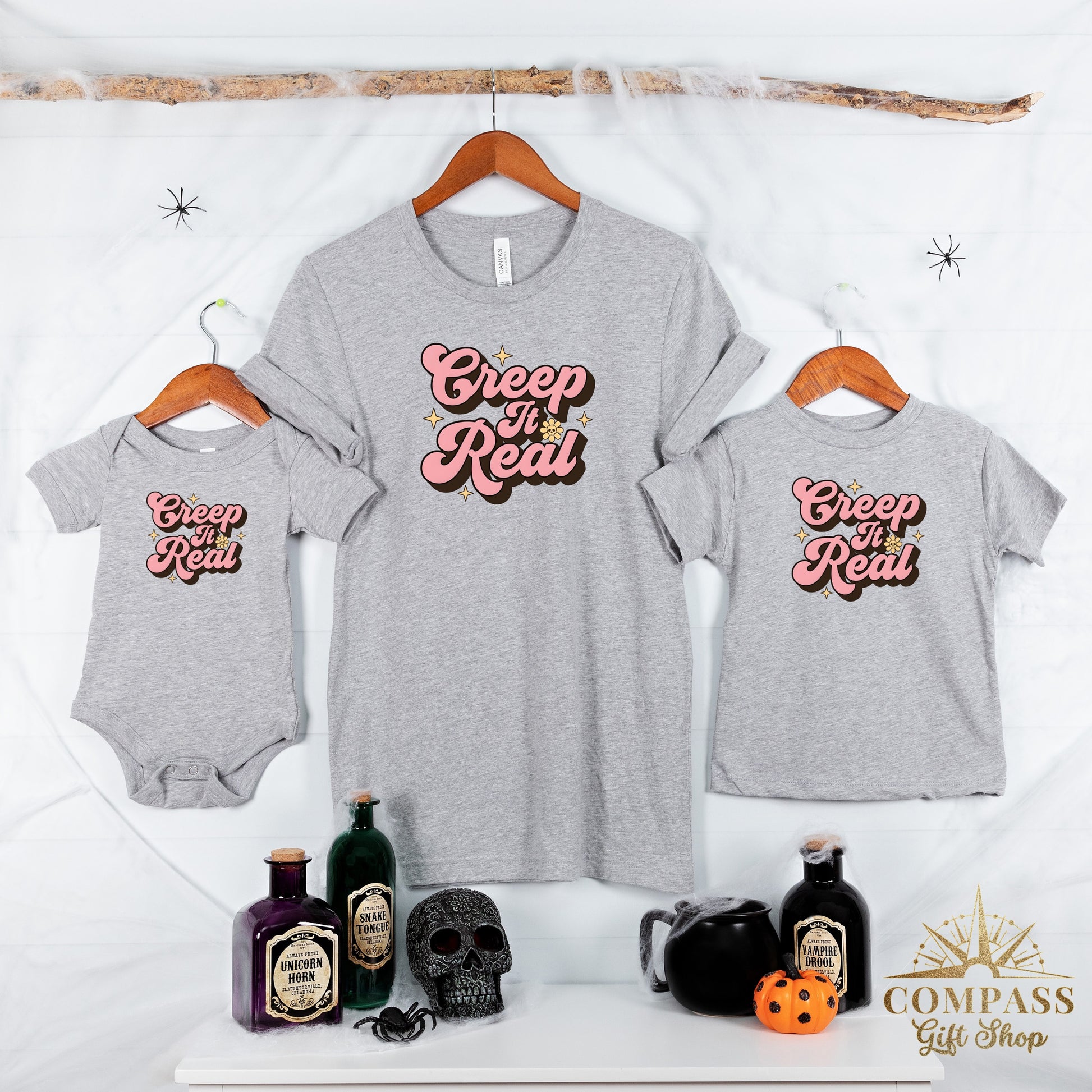 Three grey t-shirts, baby onesie displaying "Creep It Real" text and Halloween props.