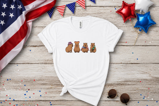 White t-shirt with four capybaras wearing patriotic hats and accessories.