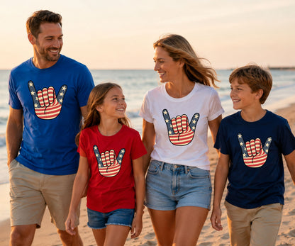 Family wearing matching American flag graphic tees on a beach.