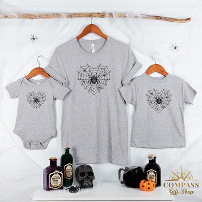 Grey t-shirts and bodysuit with spiderweb heart graphic and Halloween decor.